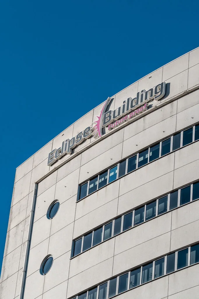 Voorgevel van het Eclipse Building aan het Rivium Quadrant met duidelijk zichtbaar logo en blauwe lucht op de achtergrond.